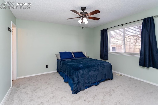 bedroom with a textured ceiling, carpet floors, and ceiling fan