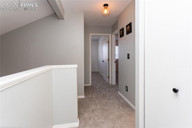 hallway with light carpet, vaulted ceiling with beams, and a textured ceiling