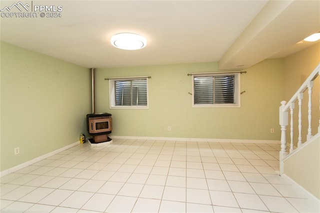 unfurnished room with light tile patterned flooring and a wood stove