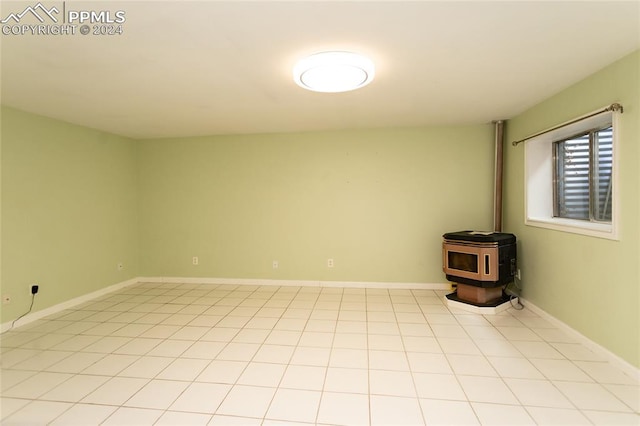 empty room with a wood stove and light tile patterned flooring