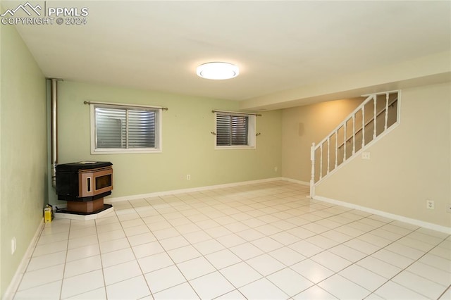 unfurnished room featuring light tile patterned floors and a wood stove