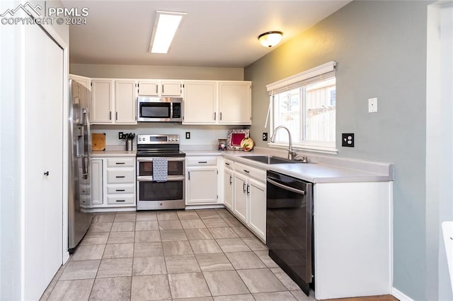 kitchen with light tile patterned floors, stainless steel appliances, white cabinetry, and sink