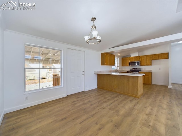 kitchen featuring pendant lighting, vaulted ceiling, appliances with stainless steel finishes, light hardwood / wood-style floors, and kitchen peninsula