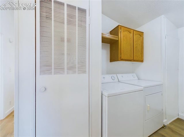 washroom with independent washer and dryer, cabinets, and light wood-type flooring