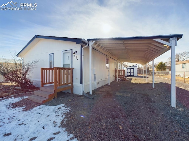 view of front of property featuring a carport and a shed