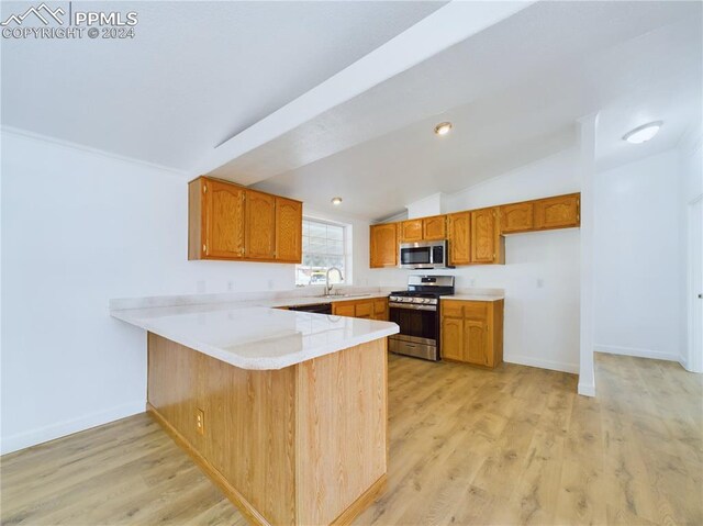 kitchen with sink, stainless steel appliances, vaulted ceiling, and light hardwood / wood-style floors