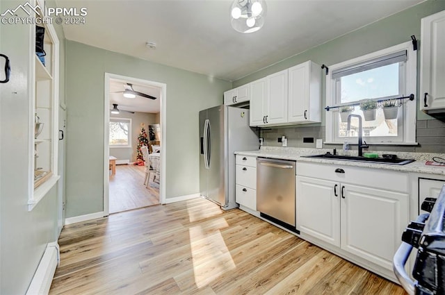 kitchen with stainless steel appliances, white cabinetry, tasteful backsplash, and sink