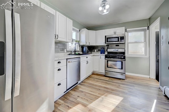 kitchen featuring tasteful backsplash, white cabinetry, sink, and stainless steel appliances