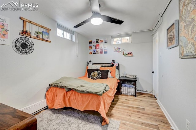 bedroom with ceiling fan, baseboard heating, and light hardwood / wood-style flooring