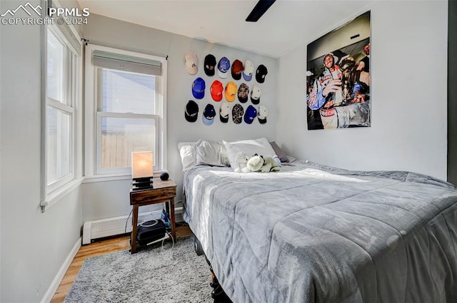 bedroom featuring ceiling fan, light hardwood / wood-style floors, and a baseboard radiator