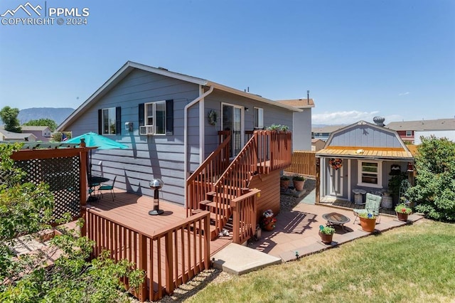 back of property with a lawn, an outbuilding, and a deck