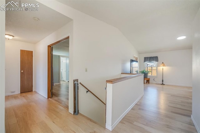 hall with light hardwood / wood-style floors and vaulted ceiling