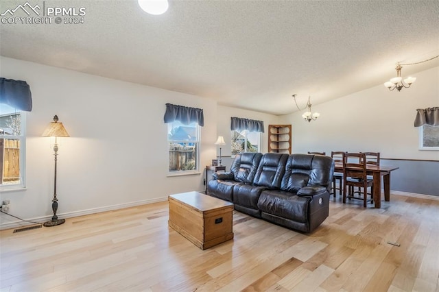 living room featuring a chandelier, a textured ceiling, and light hardwood / wood-style floors