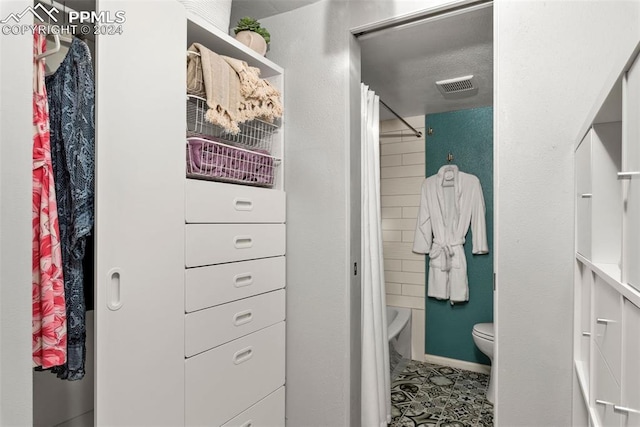 bathroom with shower / tub combo with curtain, tile patterned flooring, a textured ceiling, and toilet