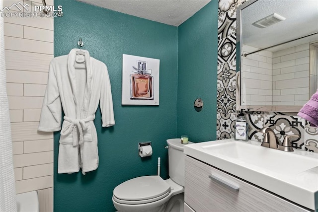 bathroom featuring backsplash, vanity, a textured ceiling, and toilet