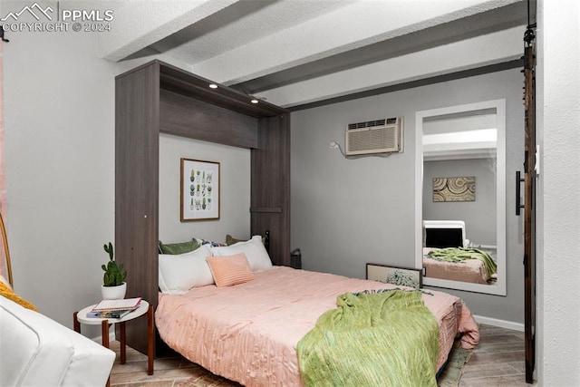 bedroom with beam ceiling, light hardwood / wood-style floors, and a wall mounted air conditioner