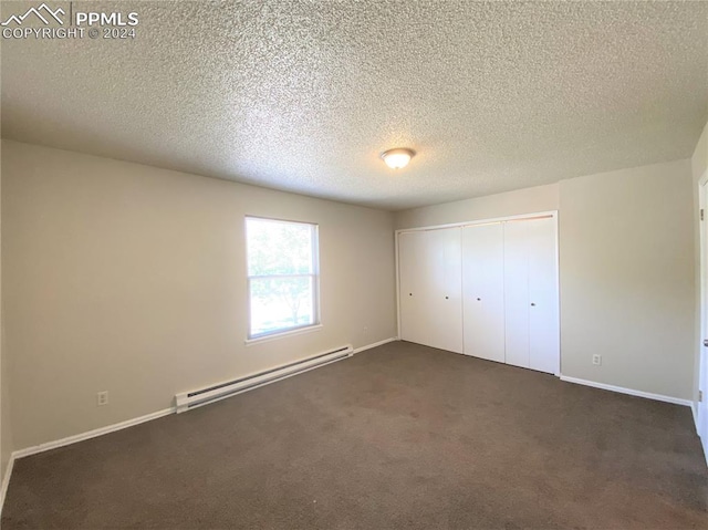 unfurnished bedroom featuring dark colored carpet, a textured ceiling, a closet, and a baseboard heating unit