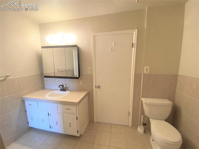 bathroom with tile patterned floors, vanity, tile walls, and toilet