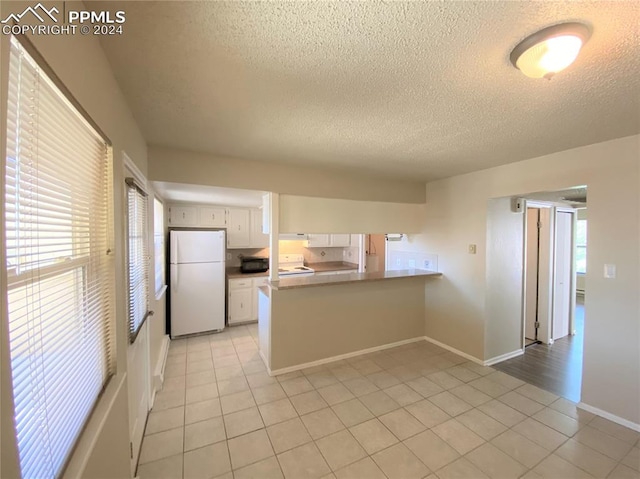 kitchen featuring white cabinets, white appliances, kitchen peninsula, and light tile patterned floors