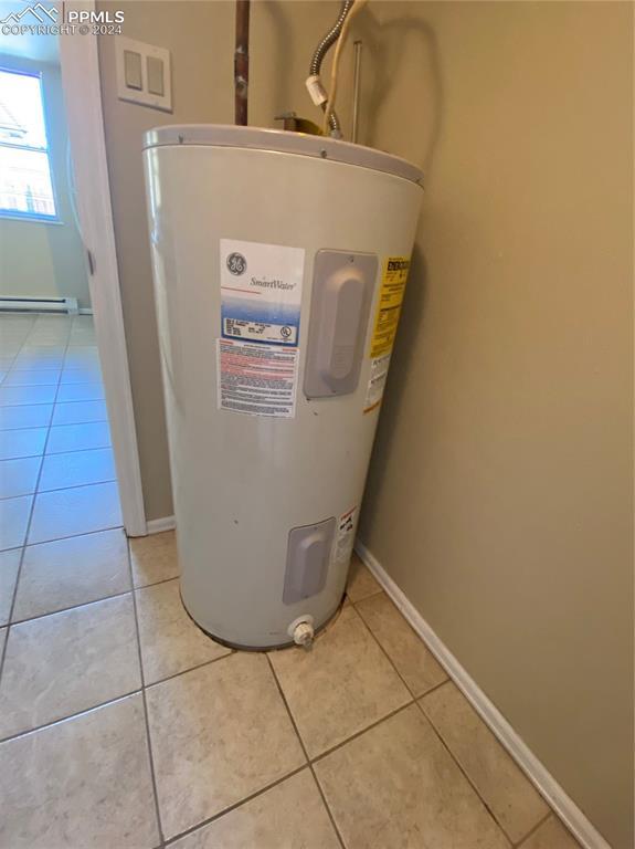 utility room featuring electric water heater and baseboard heating