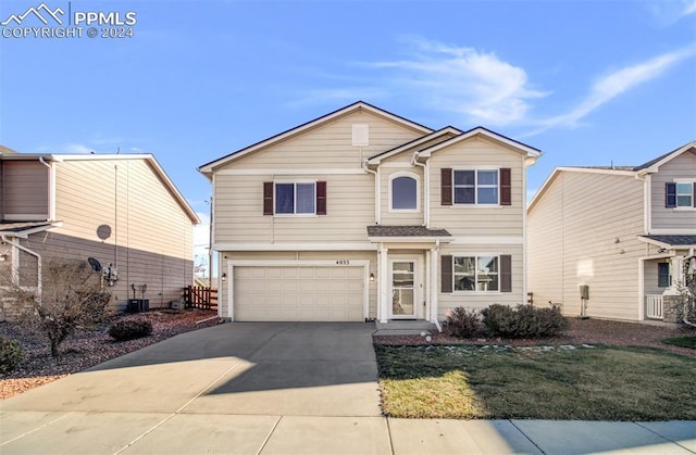 view of front of property featuring a front lawn, cooling unit, and a garage