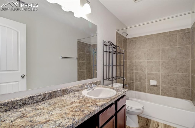 full bathroom featuring vanity, hardwood / wood-style flooring, toilet, and tiled shower / bath