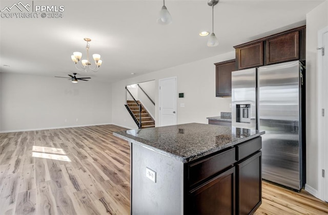 kitchen with light wood-type flooring, stainless steel refrigerator with ice dispenser, a center island, and dark stone countertops