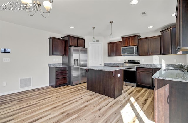 kitchen with sink, an inviting chandelier, light hardwood / wood-style floors, pendant lighting, and appliances with stainless steel finishes