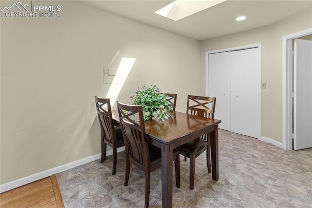 dining room featuring a skylight, baseboards, and recessed lighting