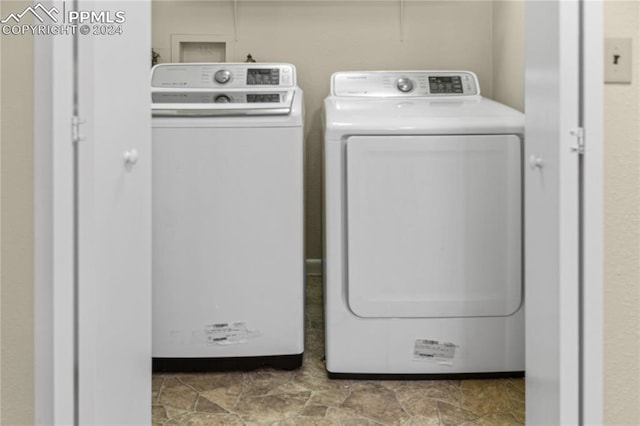 clothes washing area featuring laundry area, stone finish flooring, and independent washer and dryer