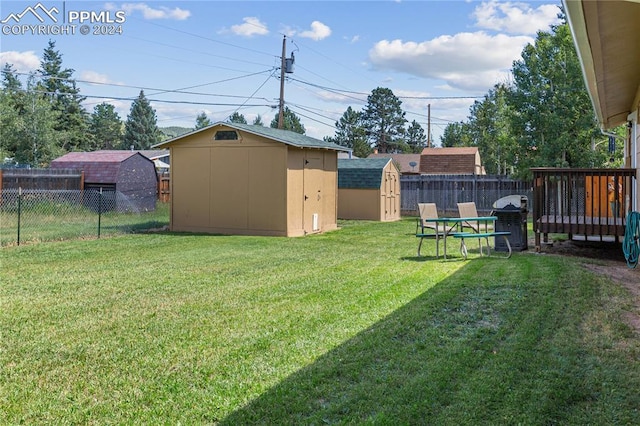 view of yard featuring a fenced backyard, an outdoor structure, a wooden deck, and a storage unit