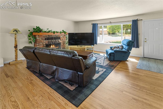 living room with light hardwood / wood-style floors and a stone fireplace