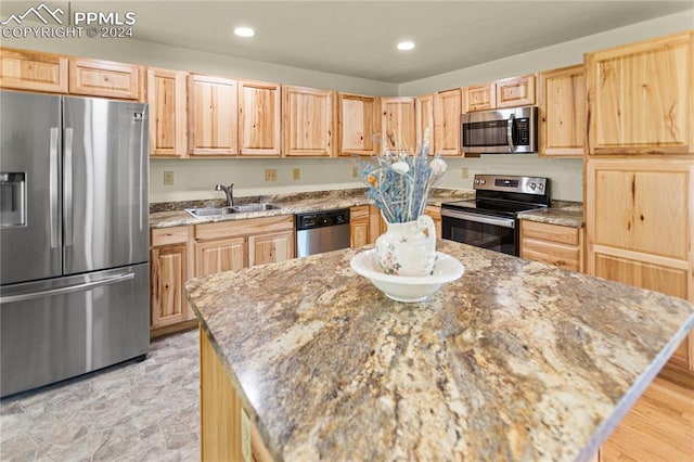 kitchen featuring light stone countertops, light brown cabinets, stainless steel appliances, and sink