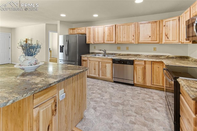 kitchen featuring appliances with stainless steel finishes, light brown cabinets, stone countertops, and sink