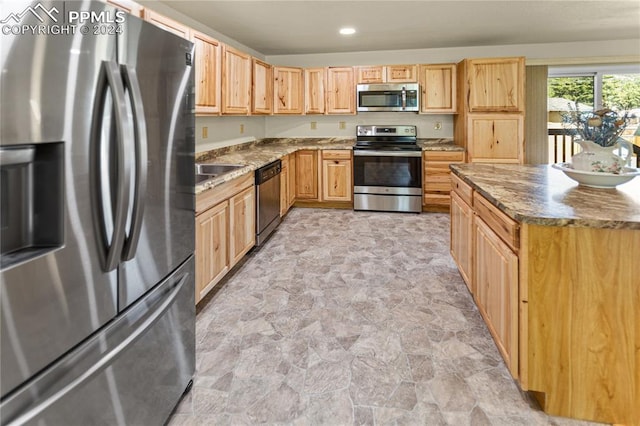 kitchen featuring stainless steel appliances, recessed lighting, stone finish flooring, and a sink