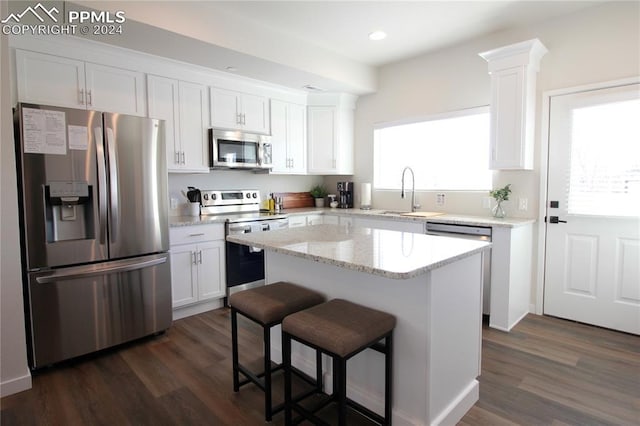 kitchen featuring white cabinets, appliances with stainless steel finishes, a center island, and dark hardwood / wood-style floors