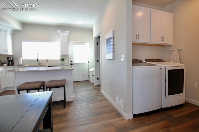 laundry area with dark hardwood / wood-style flooring, washing machine and dryer, and sink