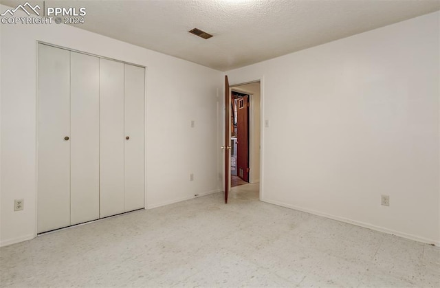 unfurnished bedroom with a textured ceiling and a closet