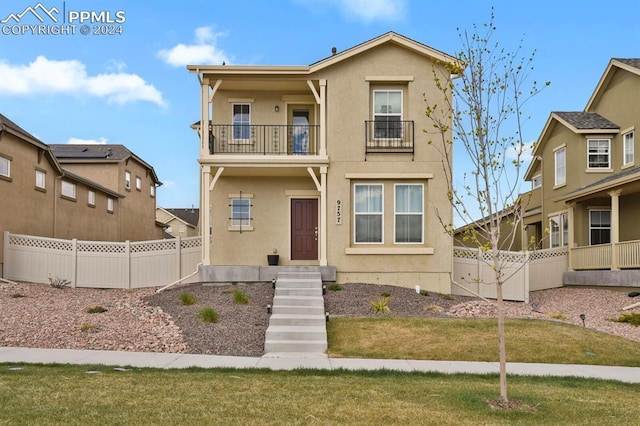 view of front facade featuring a balcony and a front yard