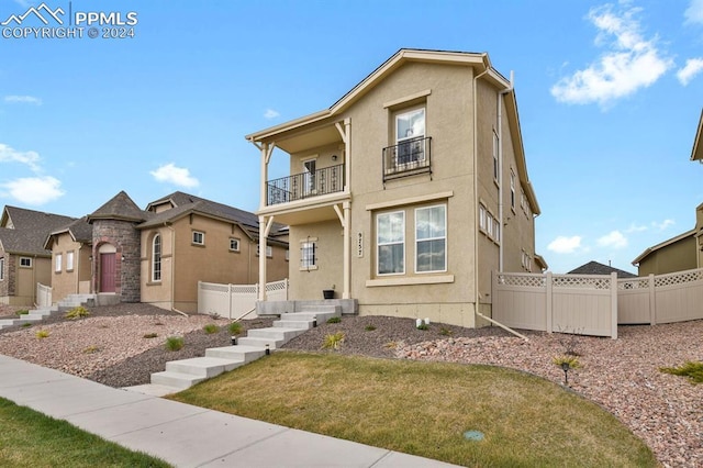 view of front of house featuring a balcony and a front lawn