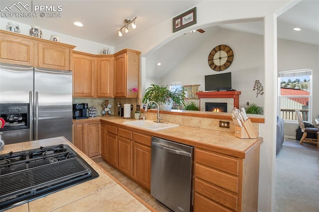 kitchen featuring tile countertops, lofted ceiling, sink, and appliances with stainless steel finishes