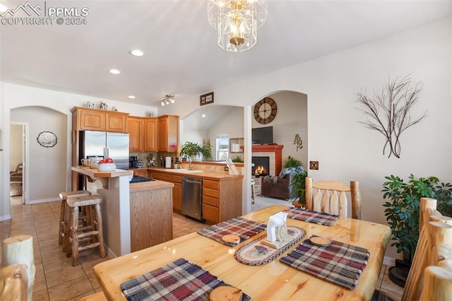 kitchen with a tile fireplace, a kitchen breakfast bar, sink, appliances with stainless steel finishes, and kitchen peninsula