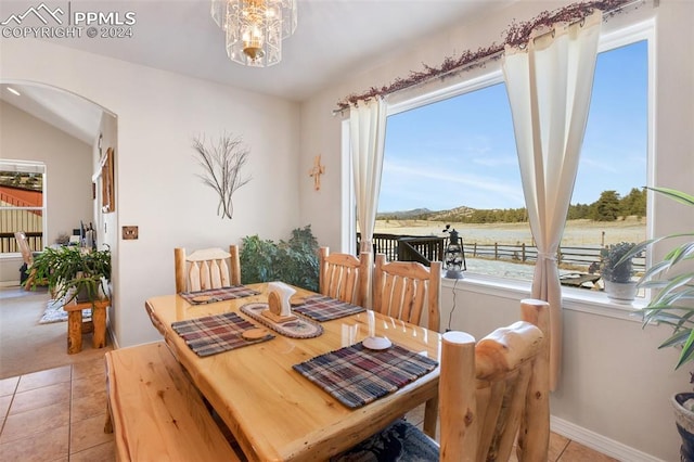 tiled dining area with a chandelier and a water view