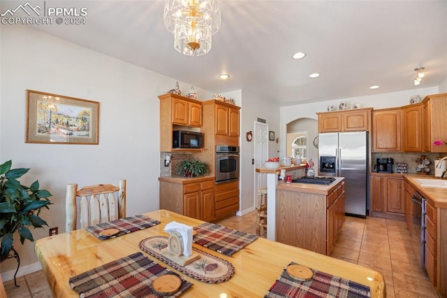 kitchen with decorative backsplash, appliances with stainless steel finishes, sink, a notable chandelier, and a center island