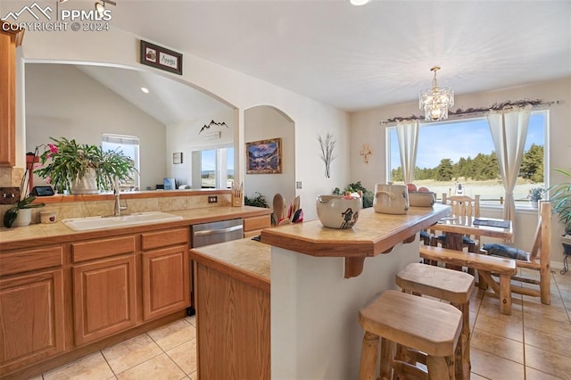 kitchen featuring dishwasher, sink, hanging light fixtures, a chandelier, and lofted ceiling