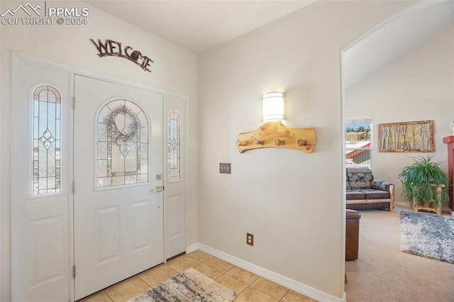 tiled entrance foyer featuring a healthy amount of sunlight and vaulted ceiling