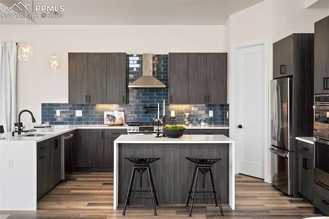 kitchen featuring light wood-type flooring, wall chimney exhaust hood, a breakfast bar, sink, and stainless steel fridge with ice dispenser