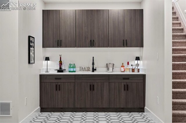 bar with dark brown cabinets and sink