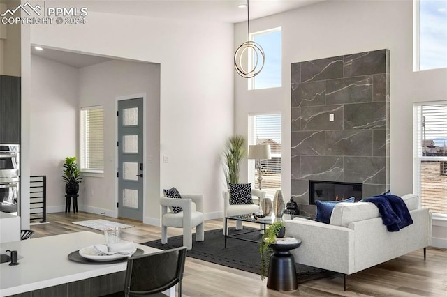 living room featuring a towering ceiling, a tile fireplace, and light hardwood / wood-style flooring