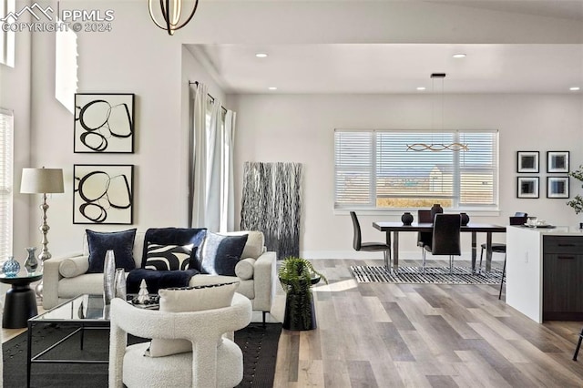 living room featuring lofted ceiling, light wood-type flooring, and a chandelier